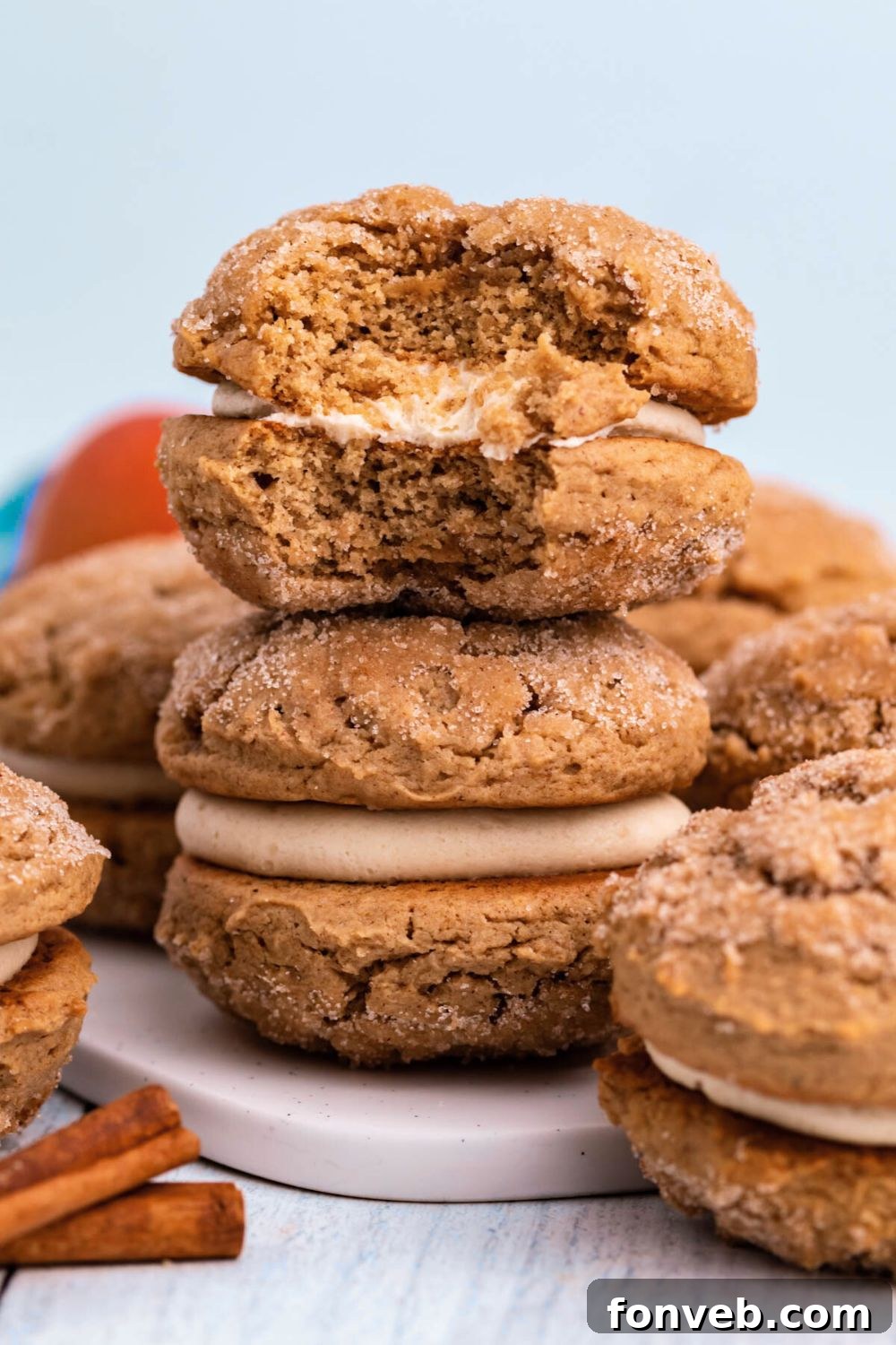 Pillowy Soft Spiced Apple Cider Whoopie Pies 8 Apple Cider Whoopie Pies stacked on a plate with one with a bite taken out of it