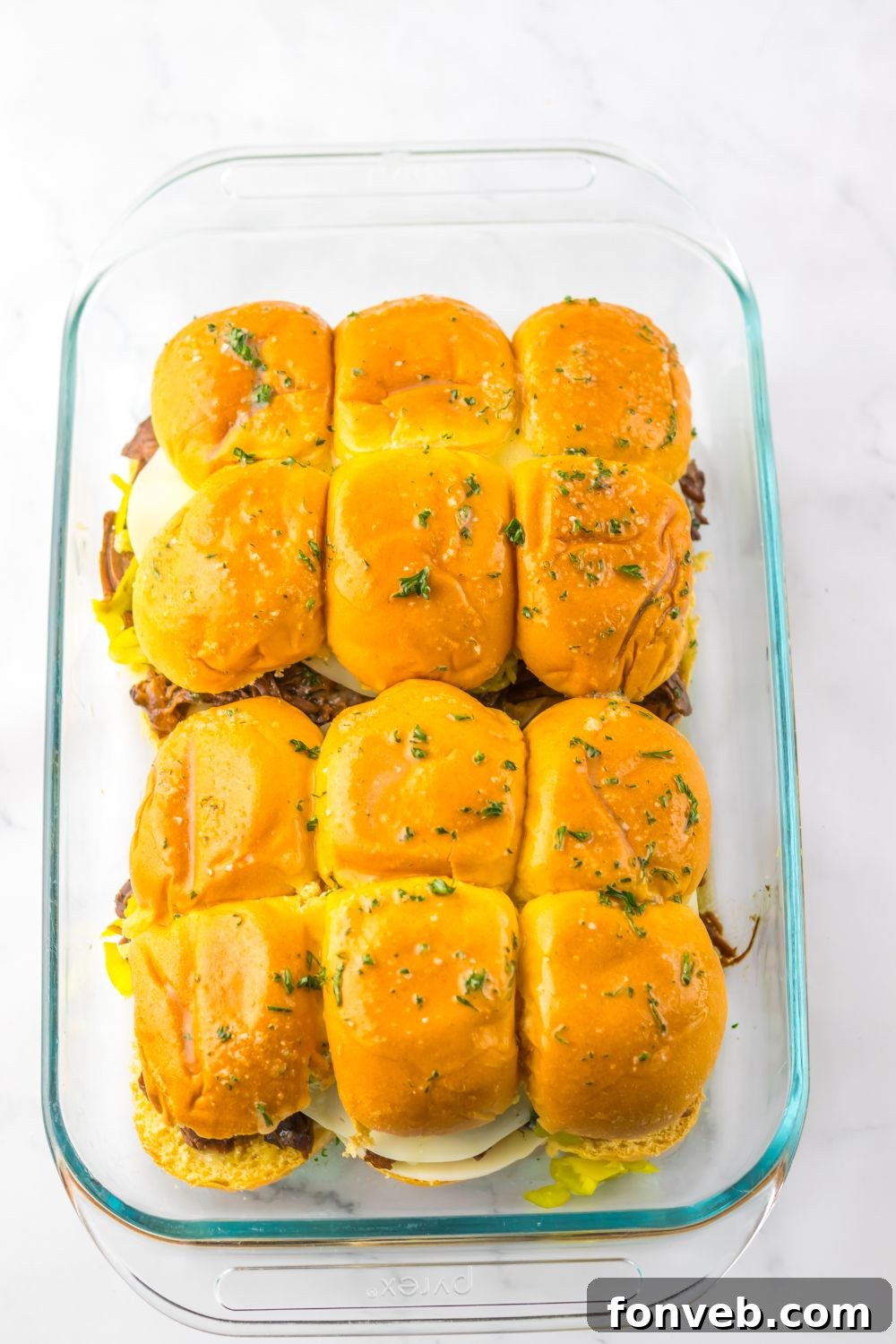 Deliciously Simple Slow Cooker Mississippi Pot Roast Sliders 12 Slow Cooker Mississippi Pot Roast Sliders assembled and being topped with parsley butter