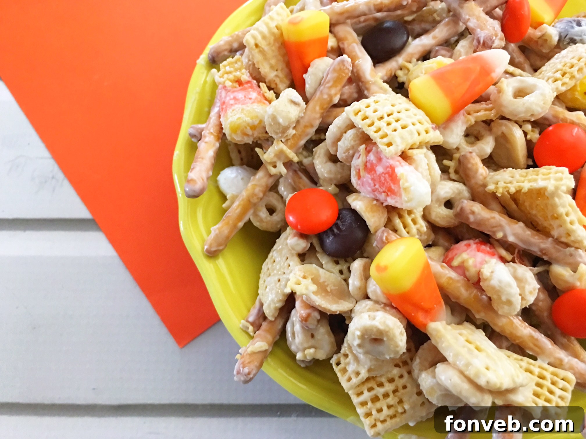 A large bowl filled with Fall Harvest Crack, showcasing pretzels, cereals, M&Ms, and candy corn.