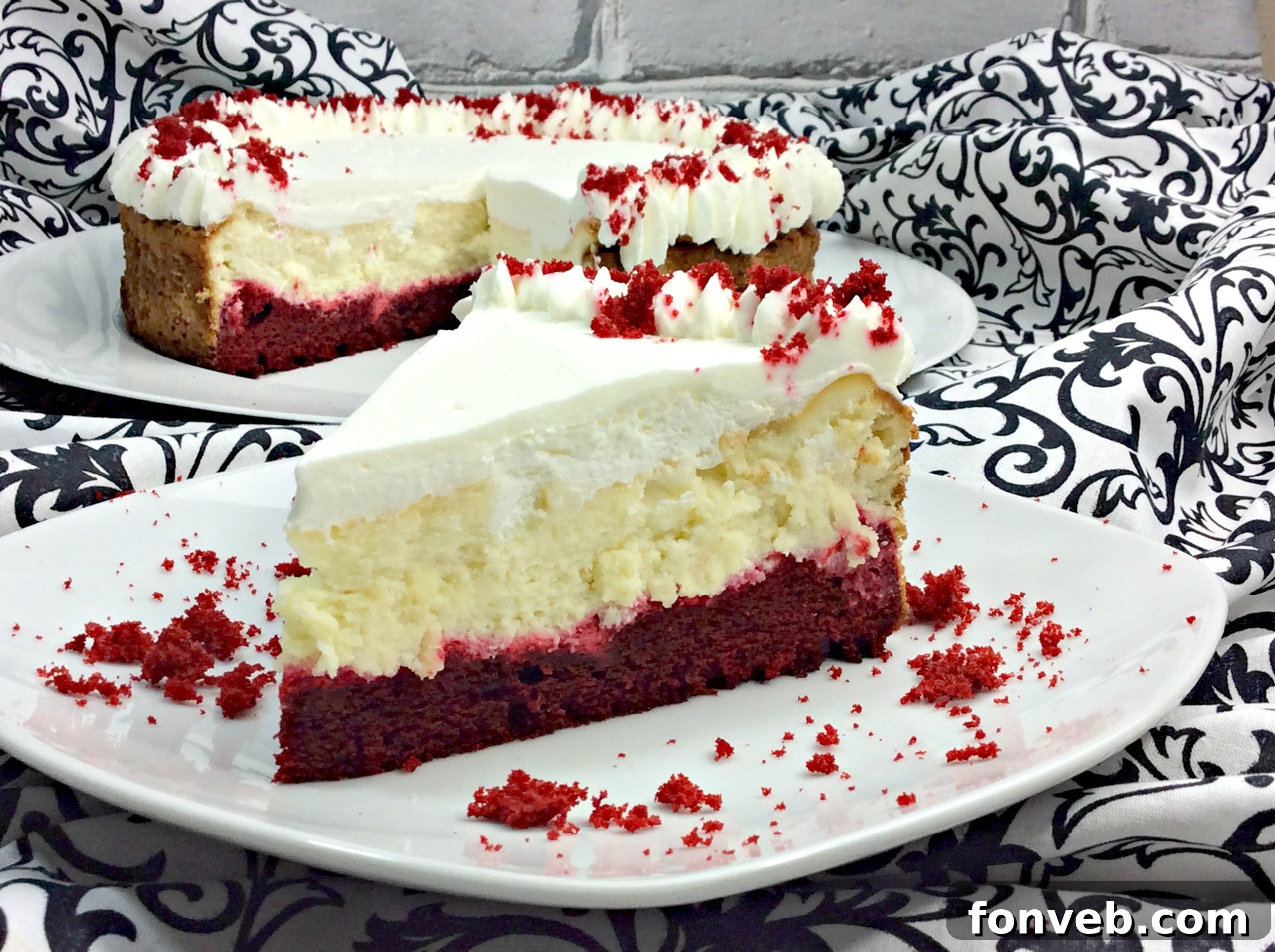 Close-up of a Red Velvet Cheesecake slice showing the moist cake, creamy cheesecake, and whipped cream layers