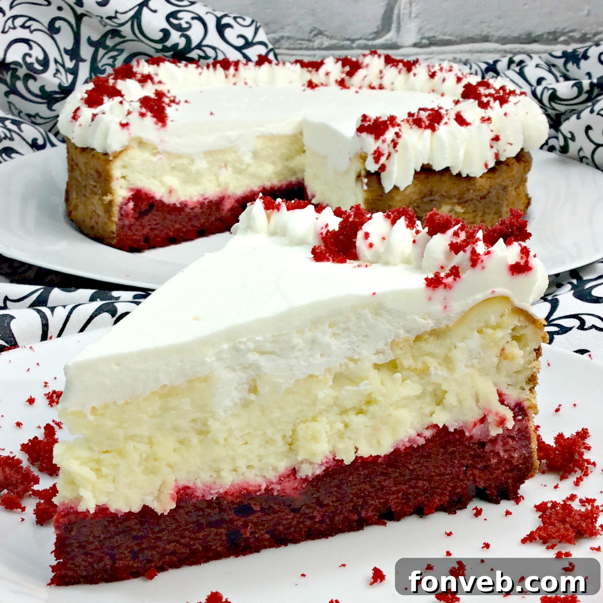 Beautifully decorated Red Velvet Cheesecake with piped whipped cream and cake crumbs