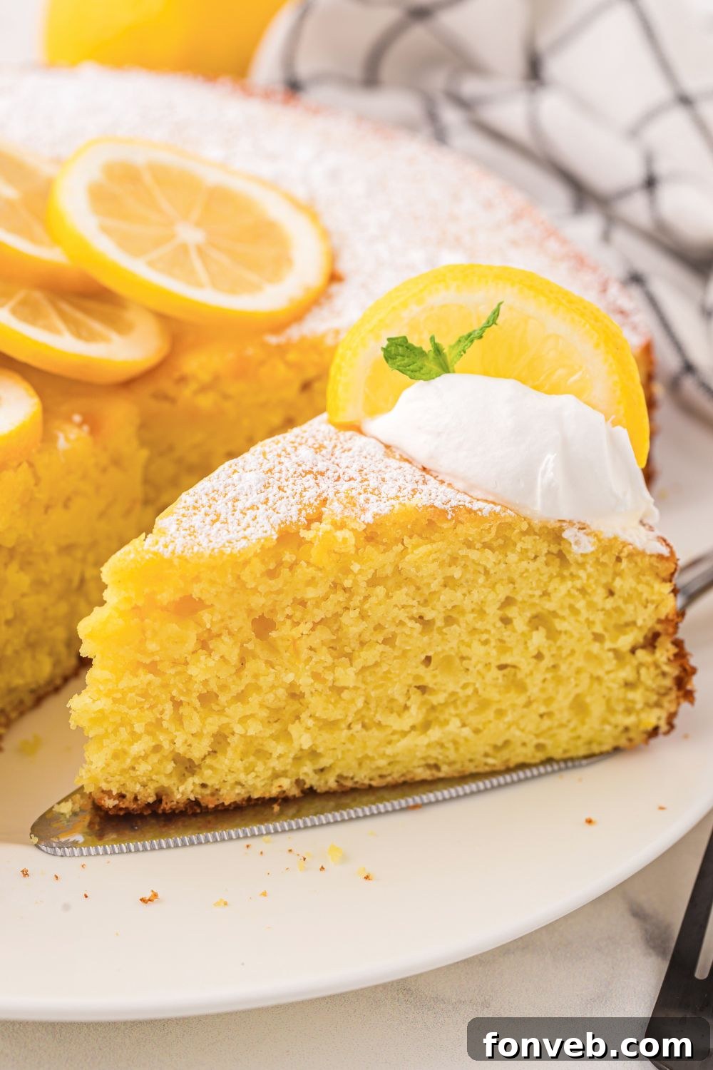 Italian Lemon Ricotta Cake on plate with a slice taken out of it 