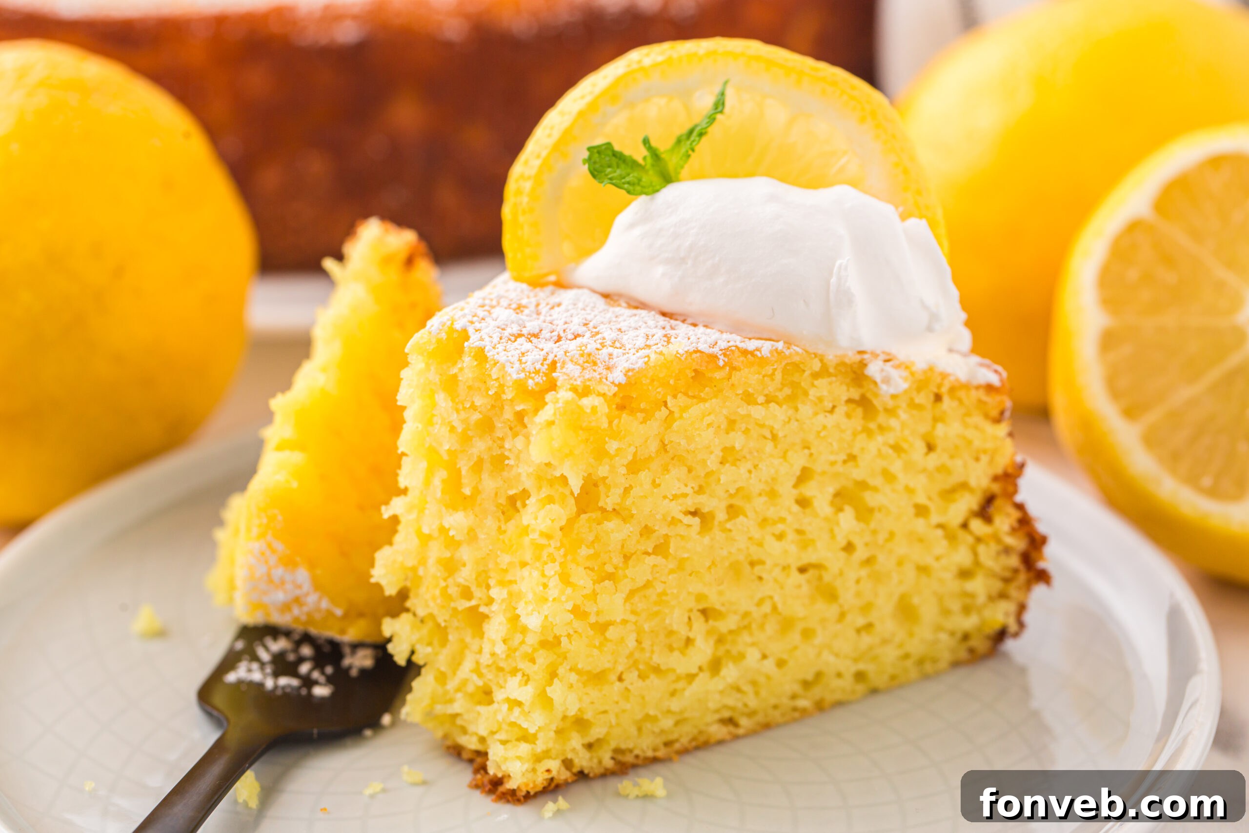 slice of Italian Lemon Ricotta Cake on a white plate with a fork taking a bite out of the slice 