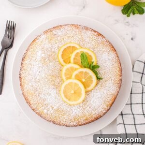 Lemon Ricotta Cake on table with some fresh lemons on top with some mint leaves to side