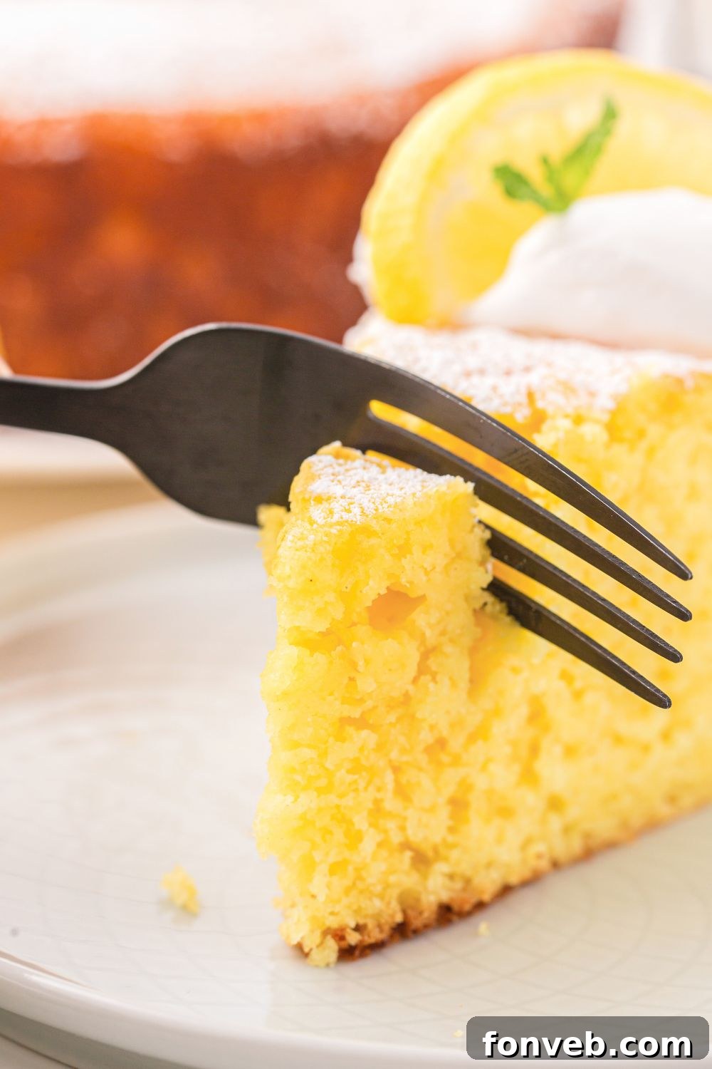piece of Italian Lemon Ricotta Cake with a fork cutting into it 