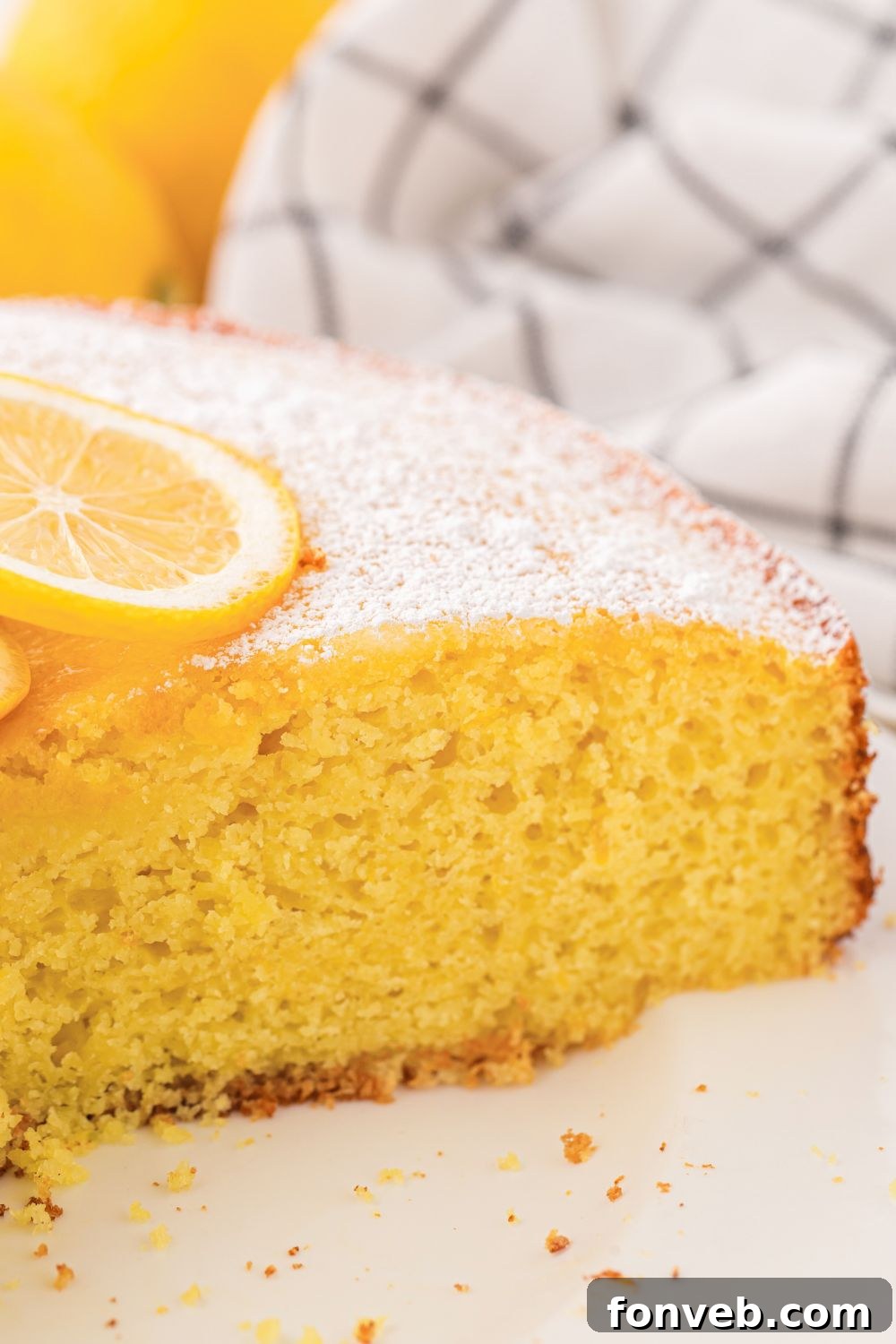 Italian Lemon Ricotta Cake sliced and placed on table with sliced lemon on top of cake 