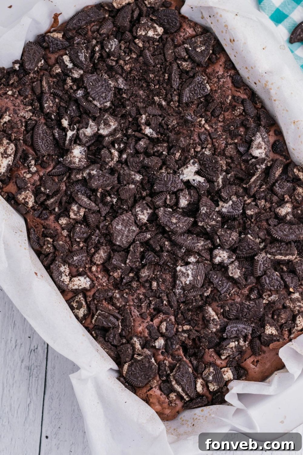 Decadent Oreo Stuffed Fudgy Brownies 7 Oreo Stuffed Brownies in a pan with parchment paper sitting on table