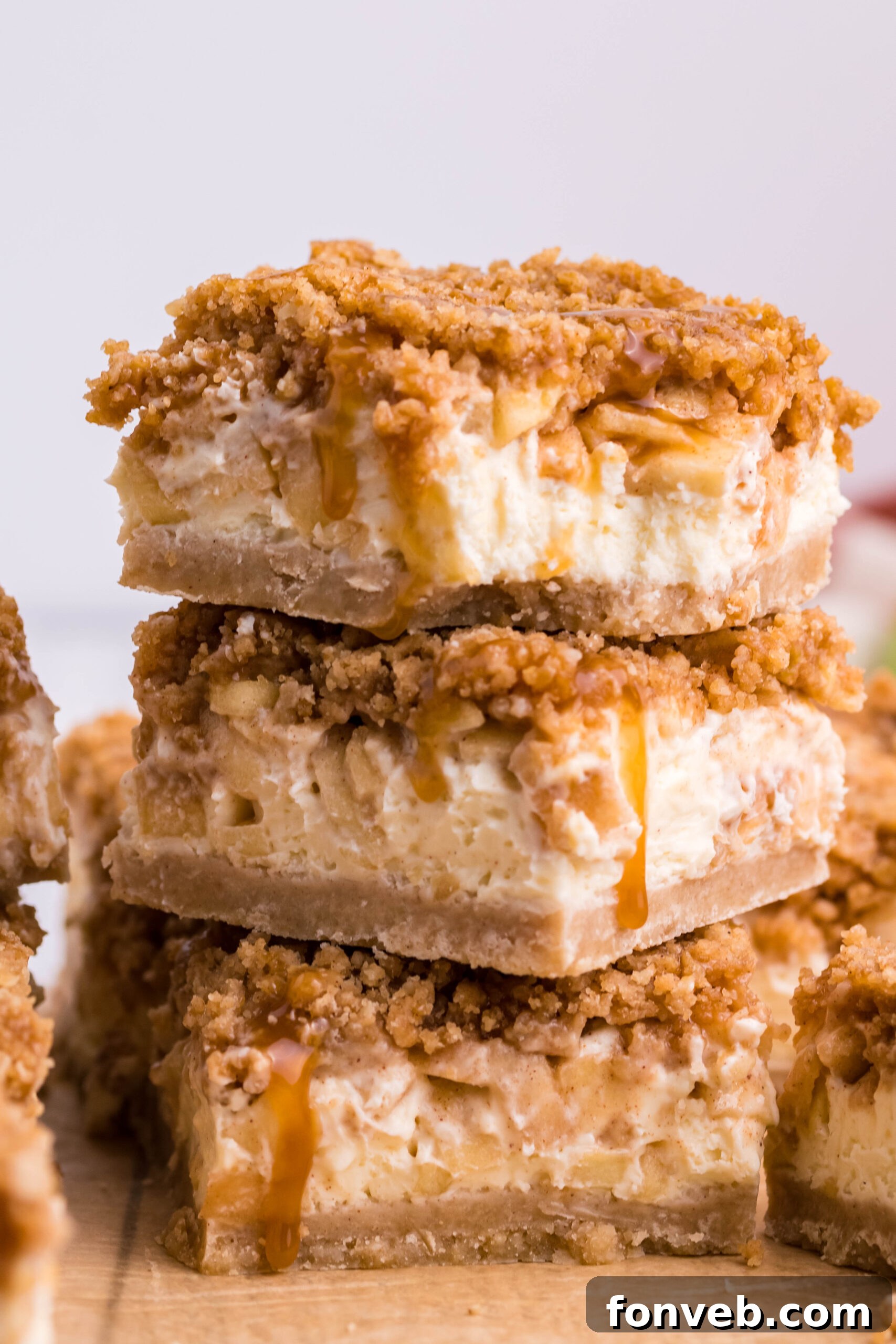 Stack of three Caramel Apple Cheesecake Bars sliced on a table 