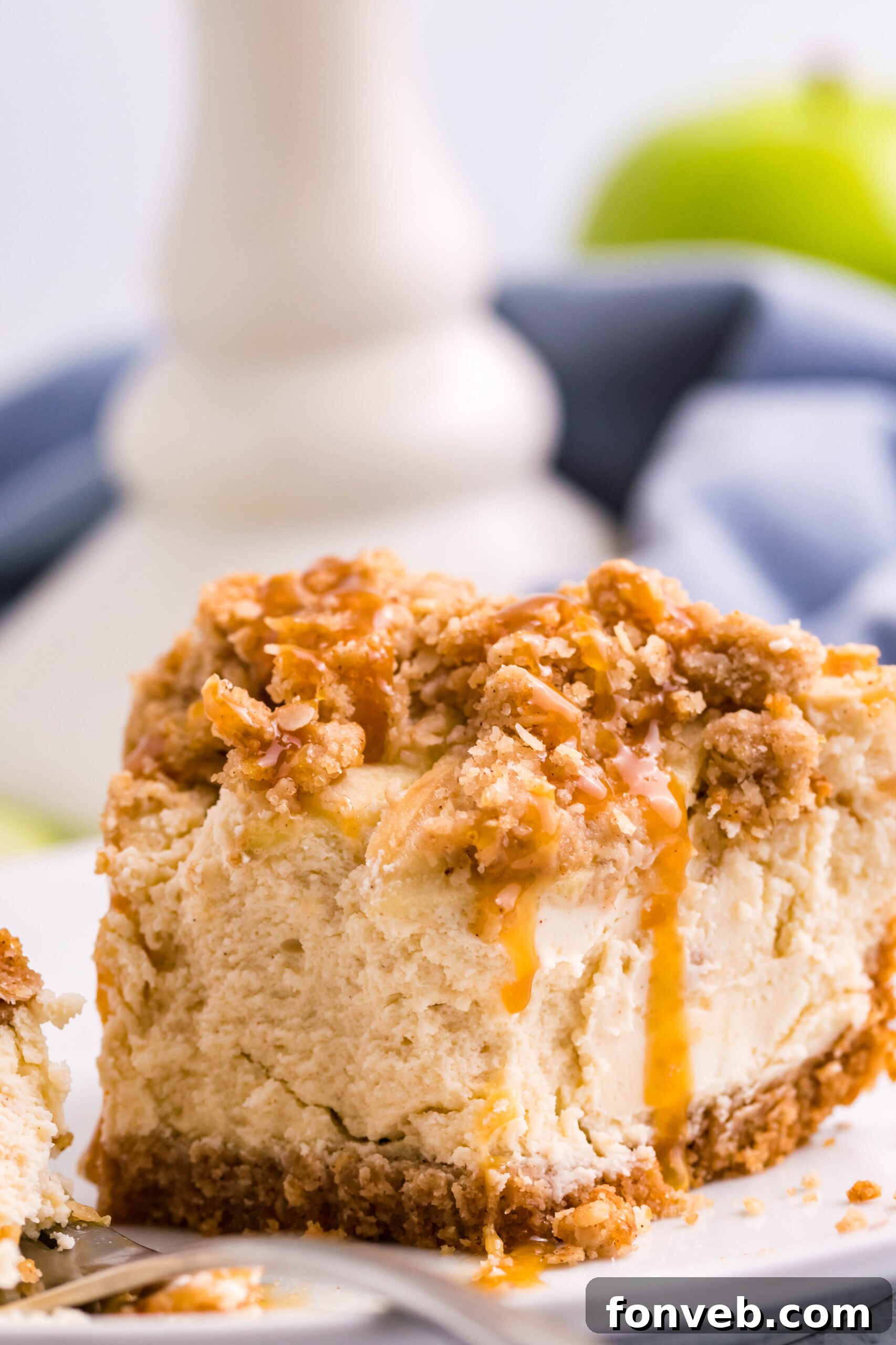 Decadent Caramel Apple Crumble Cheesecake 9 A slice of Caramel Apple Crisp Cheesecake with a small bite missing, emphasizing its deliciousness and inviting texture.