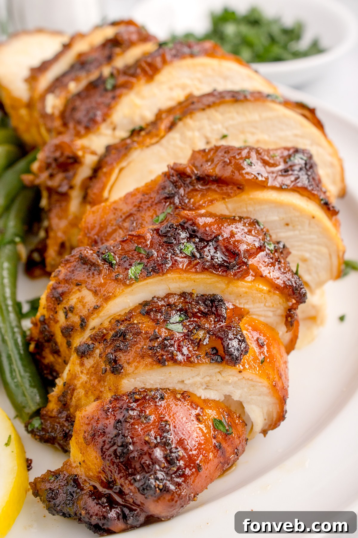 Air Fryer Chicken Breast sliced on table with some vegetables to side of the chicken