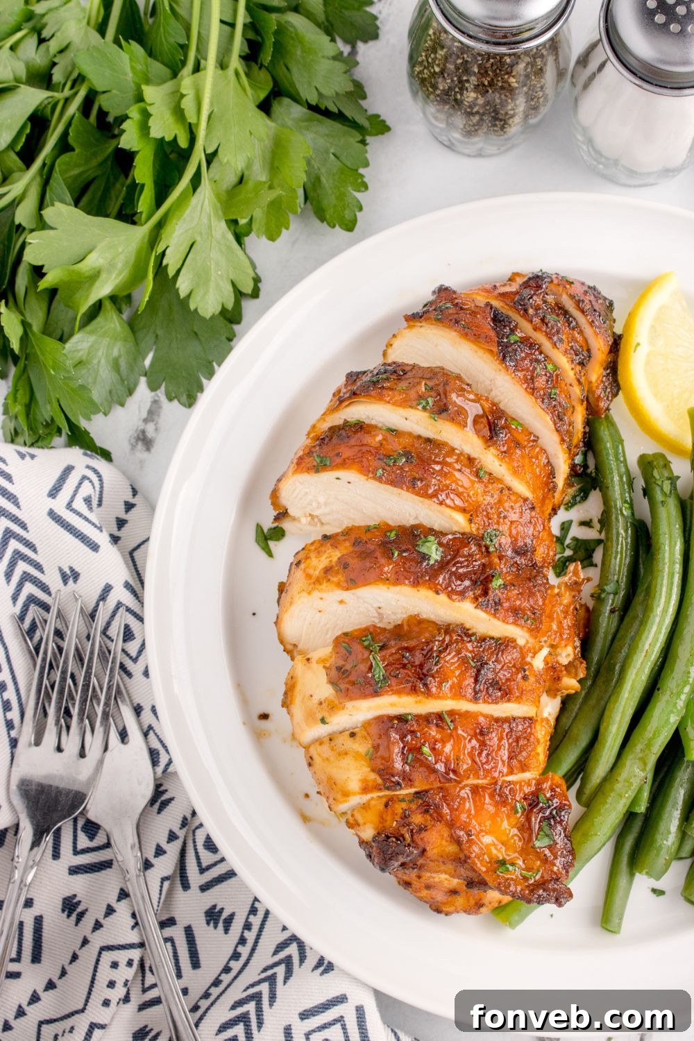 Air Fryer Chicken Breast sliced and placed on plate with lemon wedge and green beans cooked up 