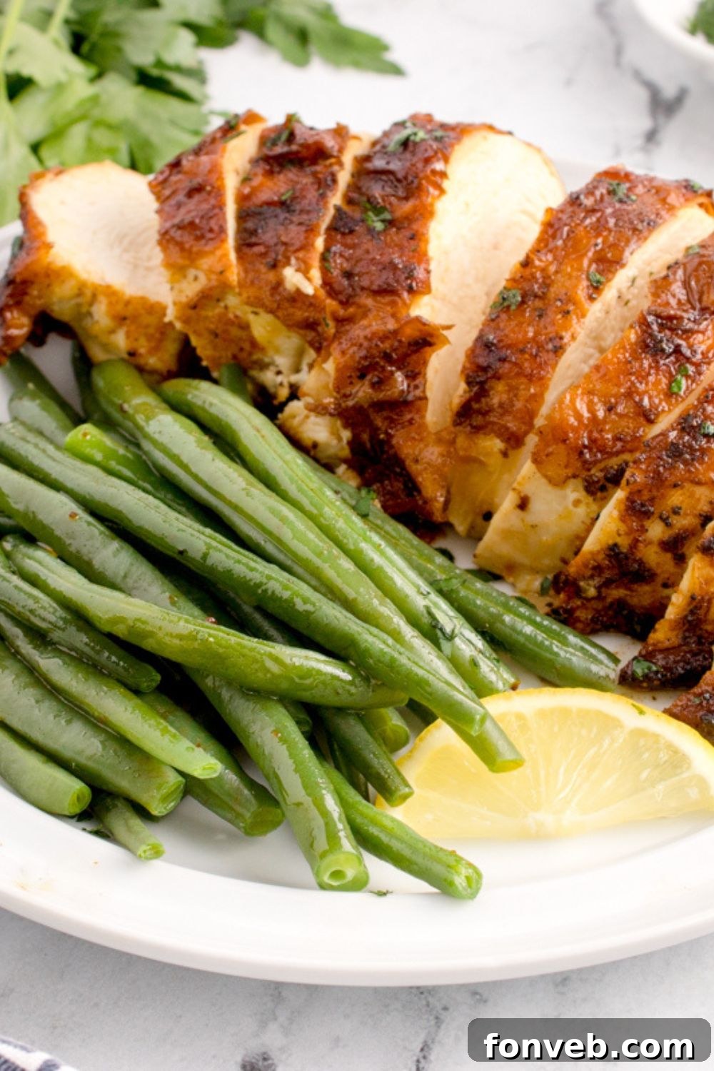 Air Fryer Chicken Breast sliced into strips with green beans and a lemon wedge 