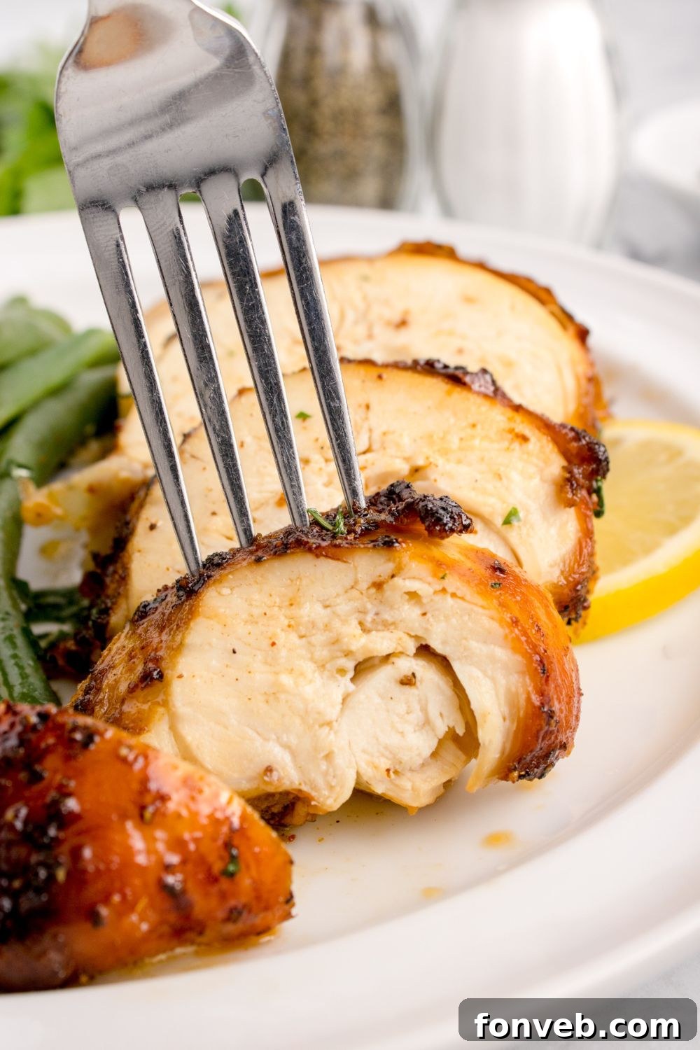 sliced Air Fryer Chicken Breast into strips with a fork poking into one of the chicken slices 
