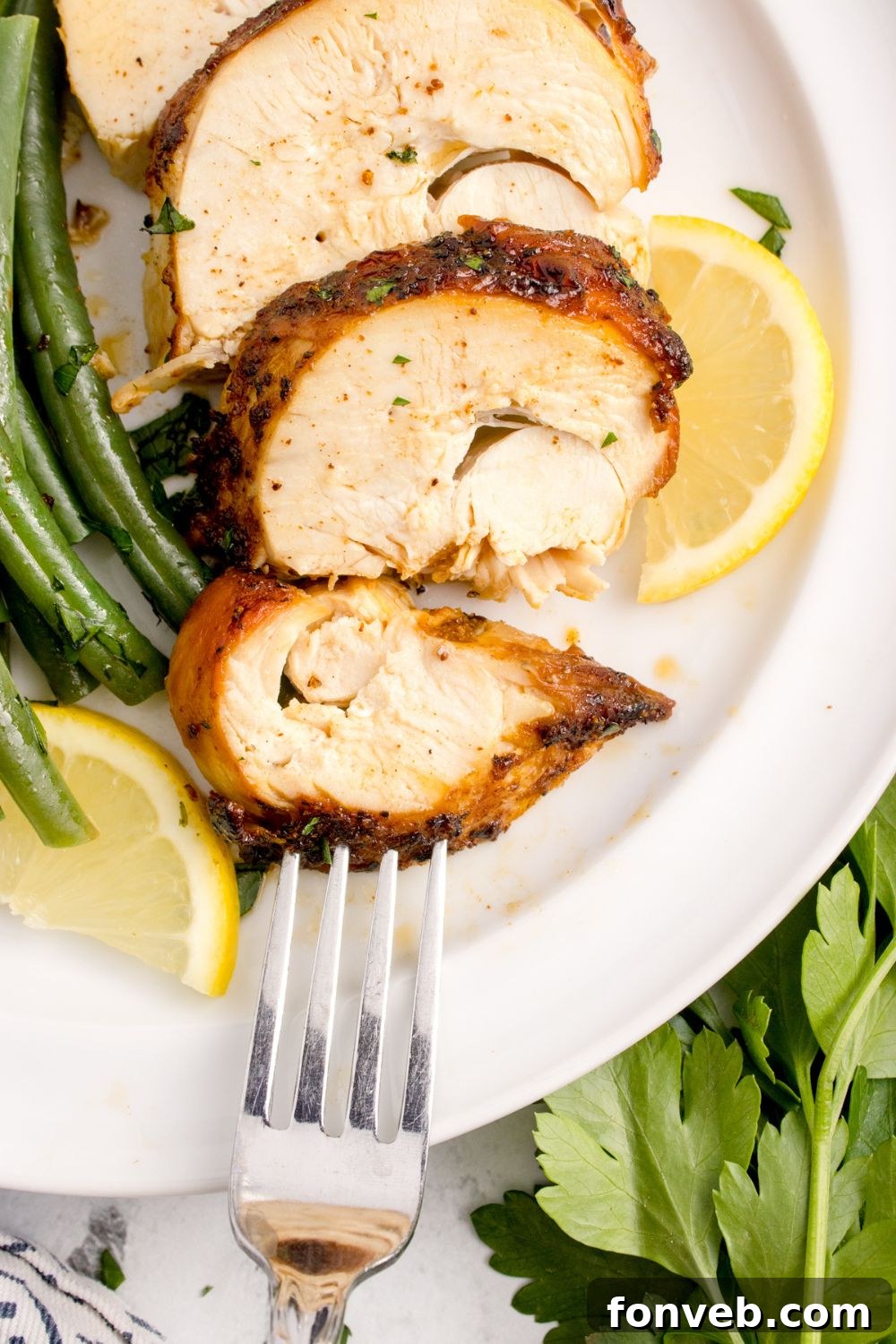 Air Fryer Chicken Breast sliced and placed on plate with lemon and green beans  for a meal 