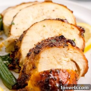 Air Fryer Chicken Breast sliced on table with some vegetables to side of the chicken