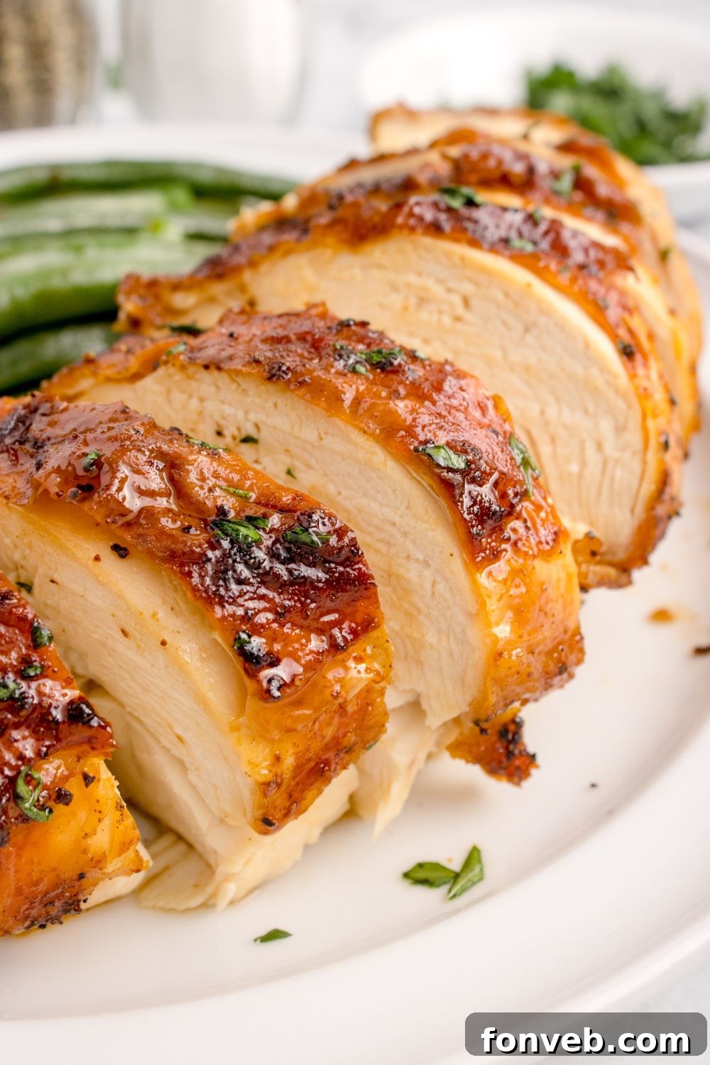 Air Fryer Chicken Breast sliced and placed on a plate with some vegetables to side of plate 