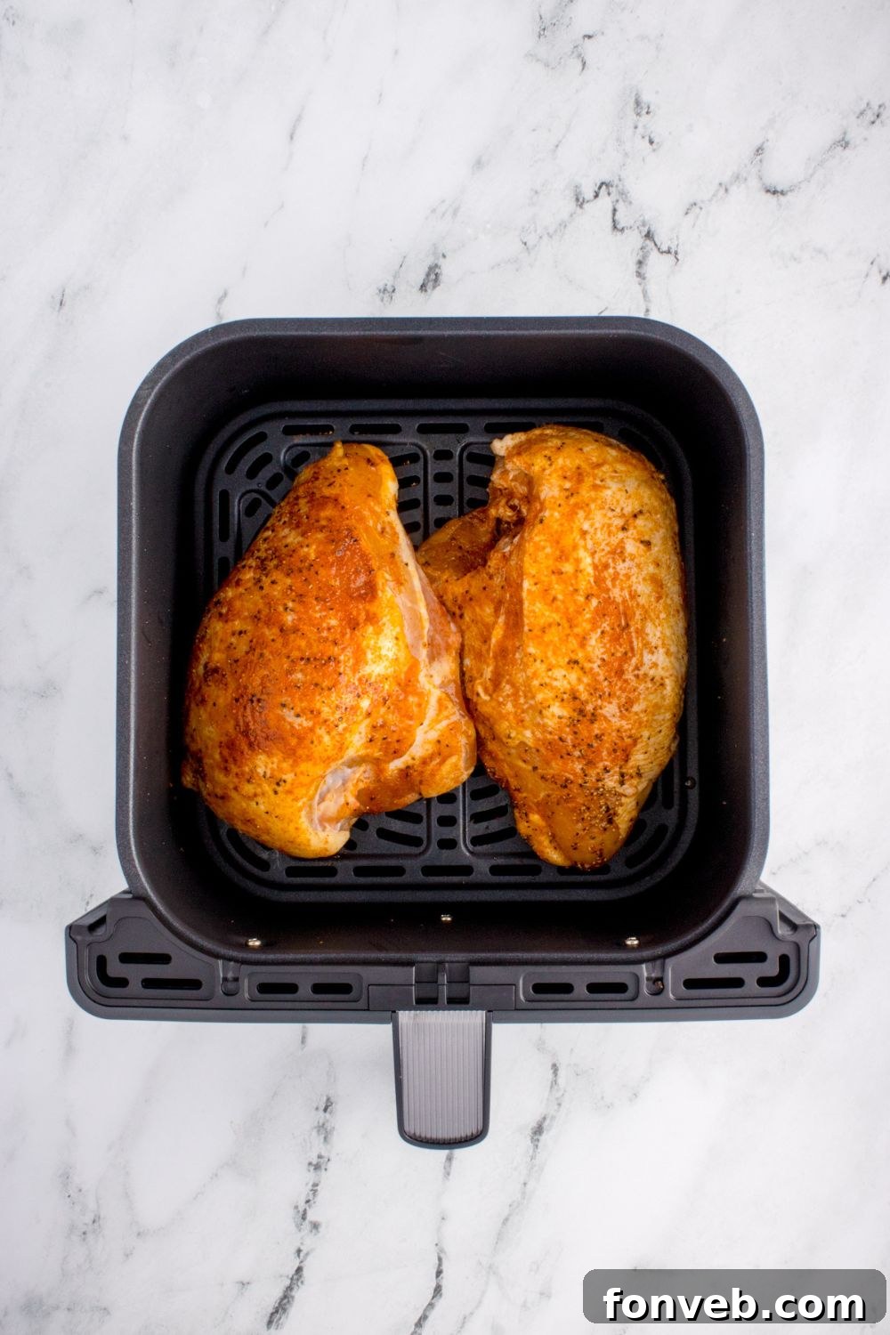 raw chicken in an air fryer basket on table for making Air Fryer Chicken Breast
