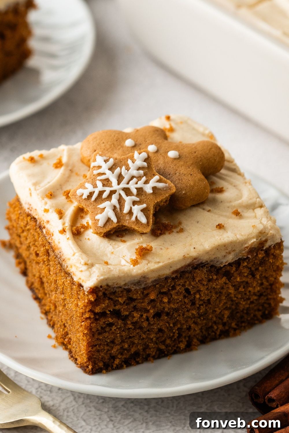 Gingerbread Cake with Cream Cheese Frosting sliced and placed on plate with cookies on top for decoration