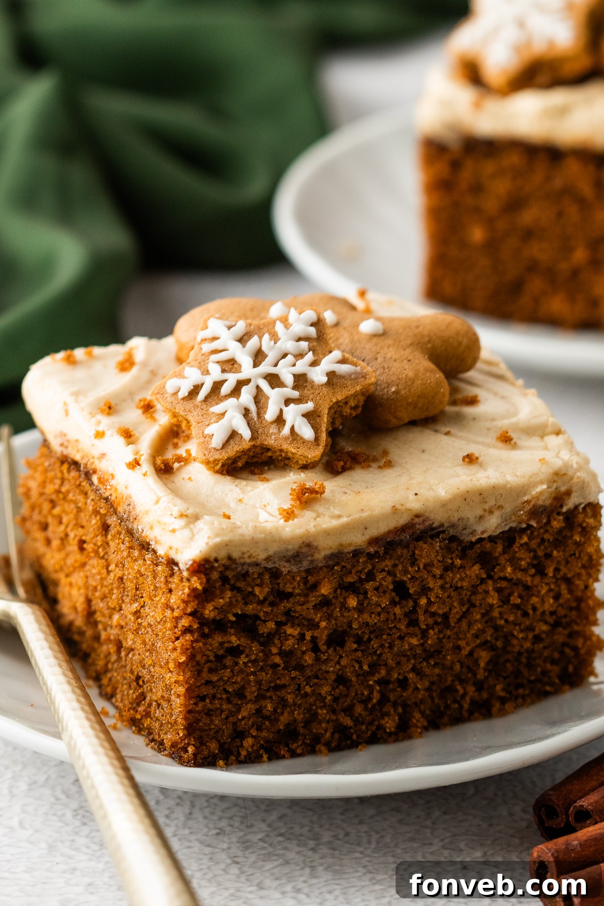Up close shot of the Gingerbread Cake with Cream Cheese Frosting on white plates with a gold fork next to the slice
