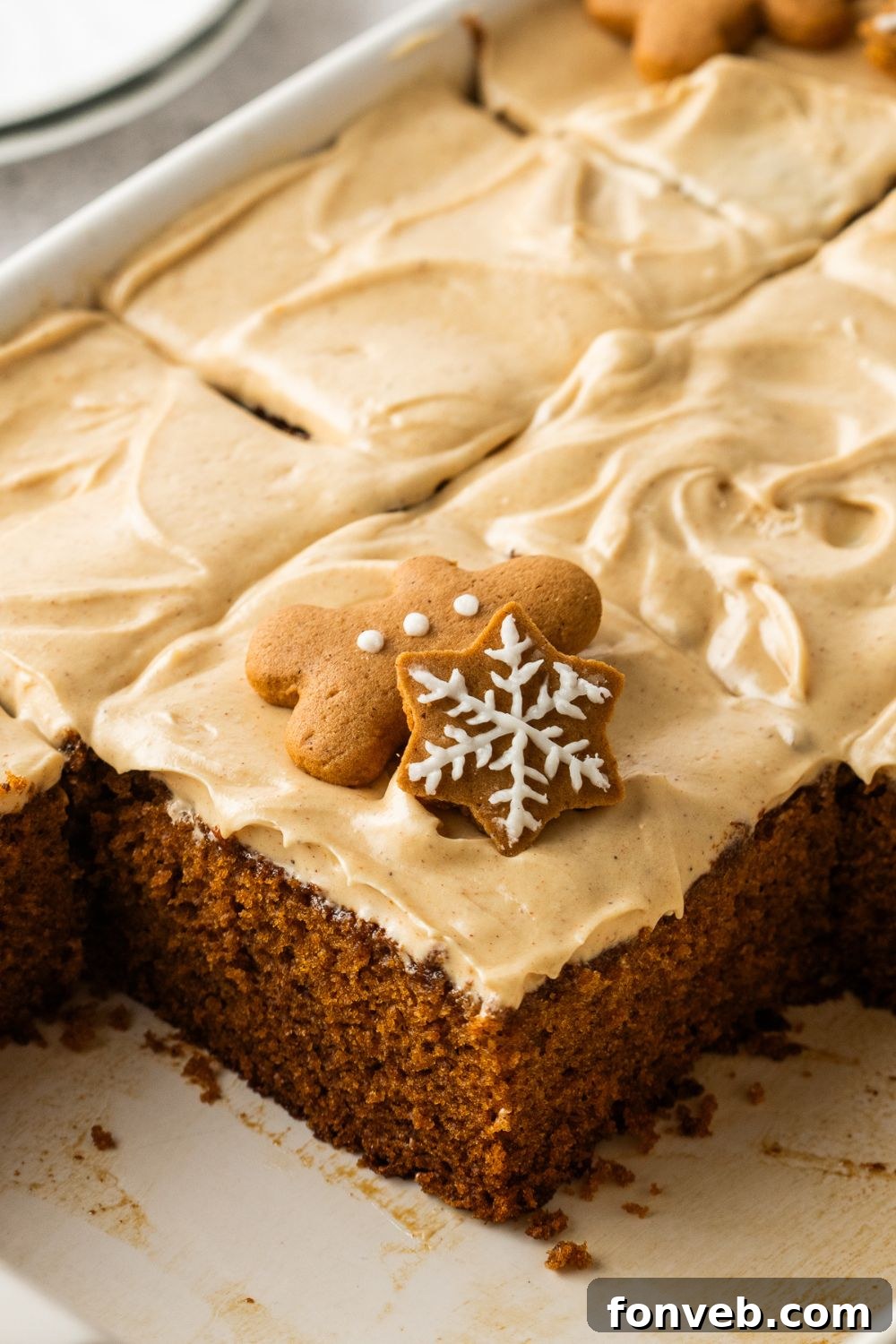 Gingerbread Cake with Cream Cheese Frosting in pan with sliced cake in it and cookies