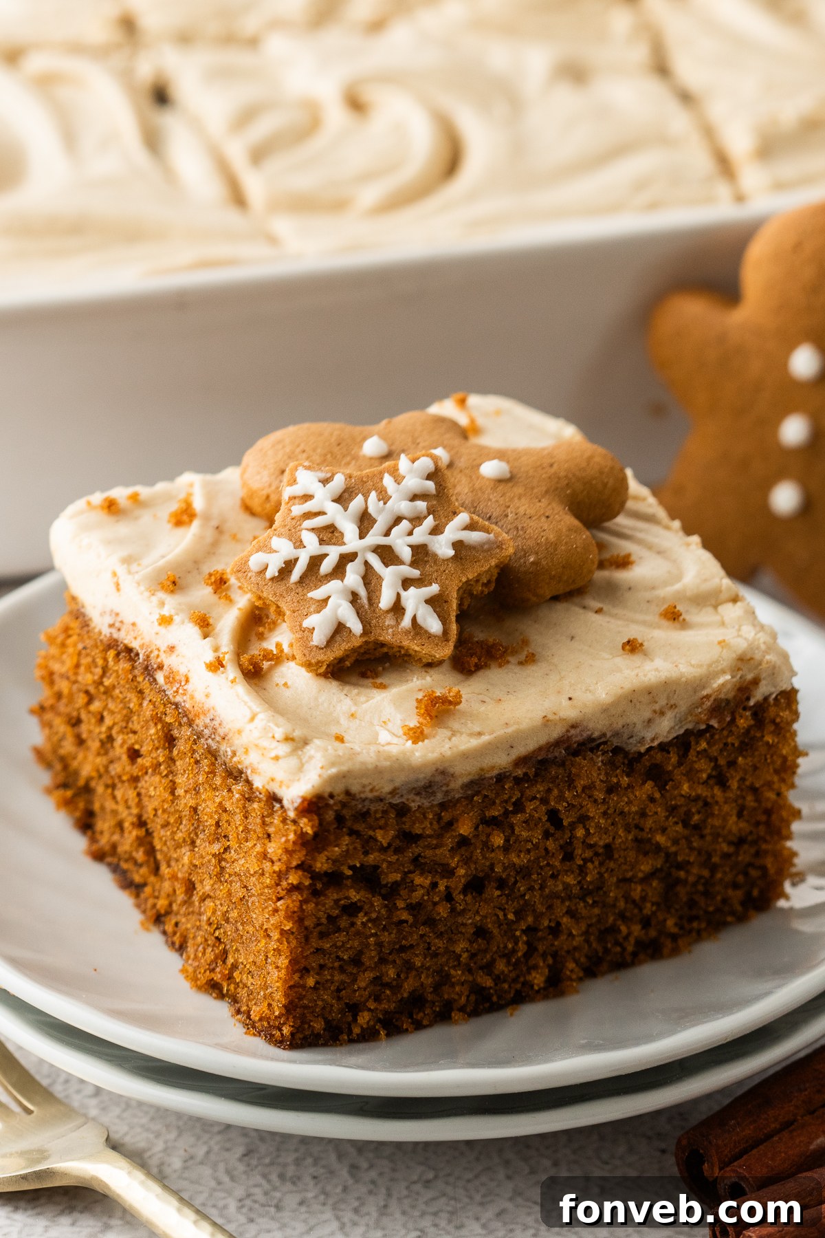 slice of Gingerbread Cake with Cream Cheese Frosting on a white plate with the whole cake pan behind