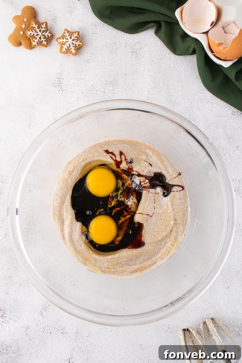 glass bowl of cake batter being mixed with some eggs and molasses on top