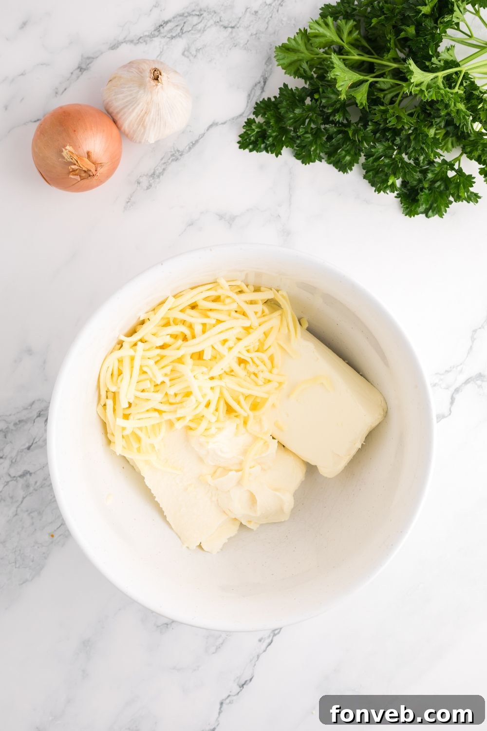 Ricotta cheese, softened cream cheese, and shredded mozzarella mixed in a glass bowl for the creamy layer