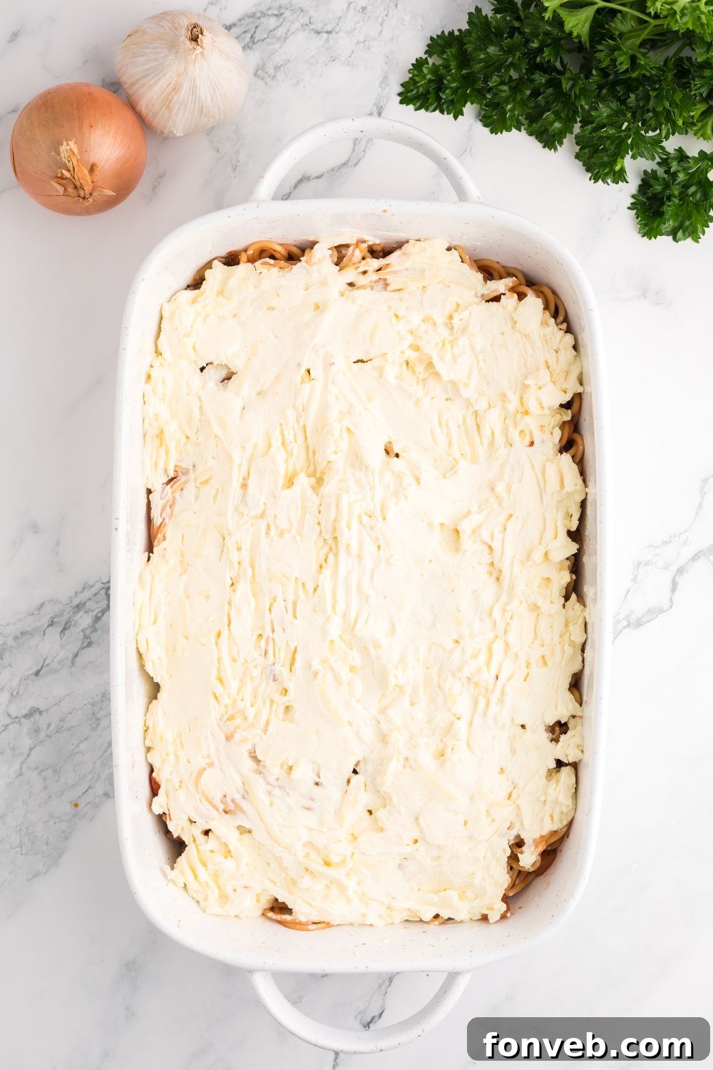 First layer of spaghetti mixture spread evenly in a rectangular glass baking dish