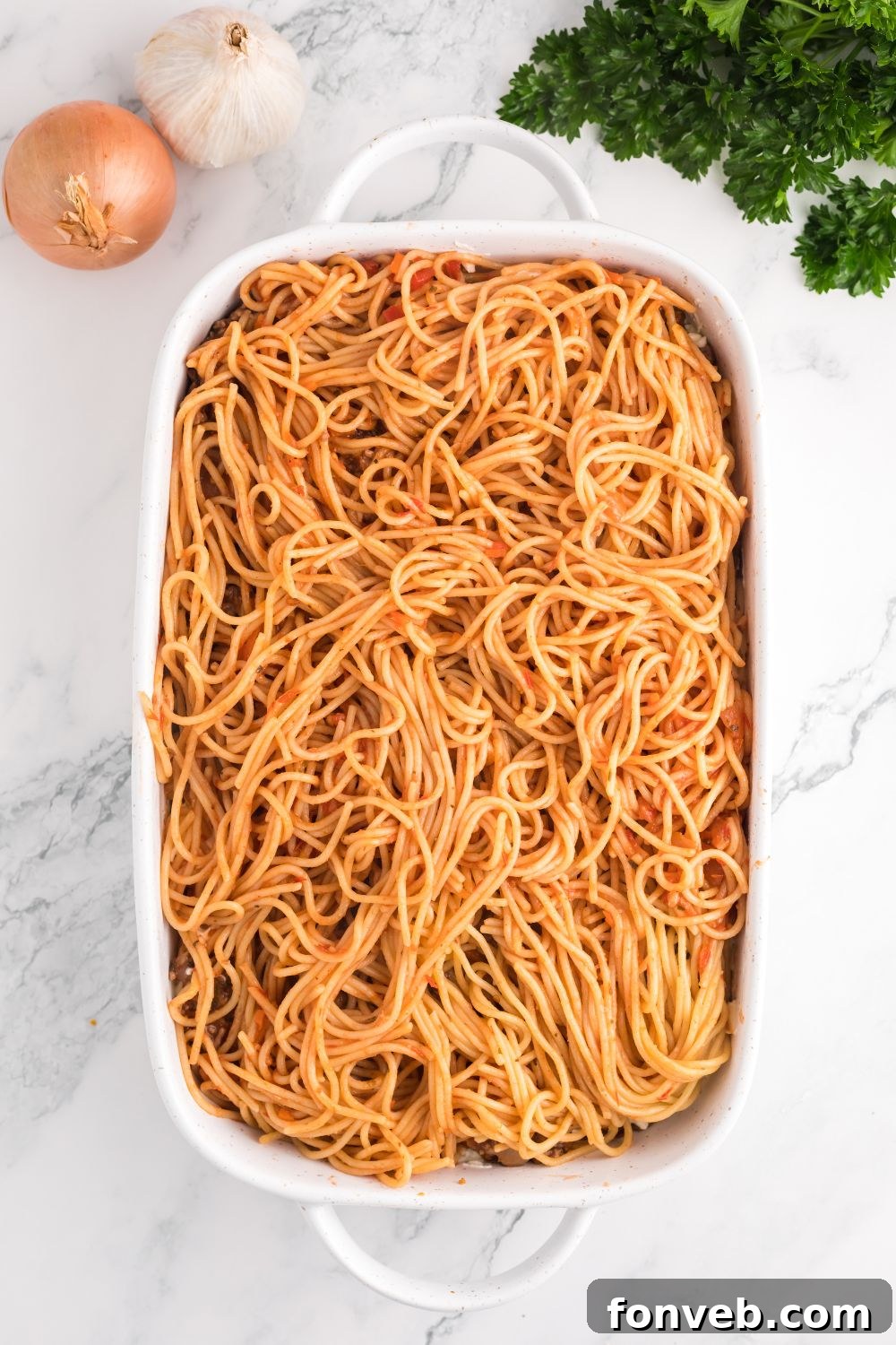 Meat sauce being added as another layer to the Million Dollar Spaghetti Casserole, building its flavorful structure