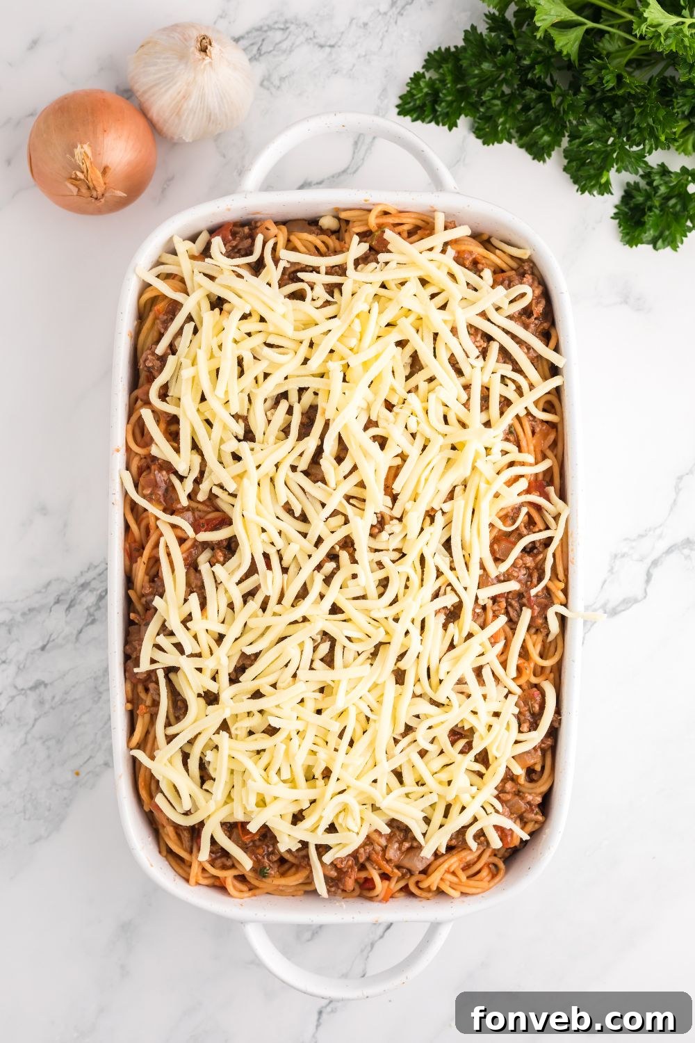 Fully assembled Million Dollar Spaghetti Casserole in a pan, generously topped with mozzarella cheese, ready for the oven