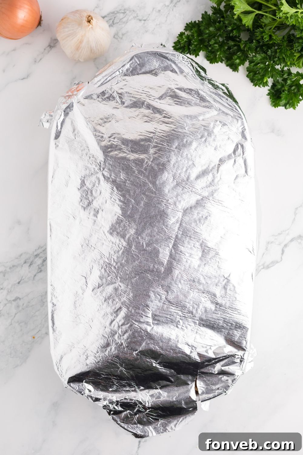 Casserole dish covered with aluminum foil, prepared for the initial phase of baking