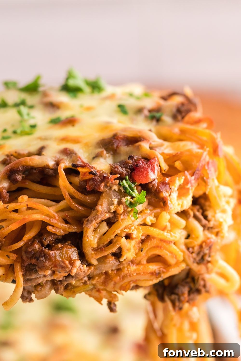 A large serving of Million Dollar Spaghetti Casserole being scooped from the pan, showing rich texture and gooey cheese