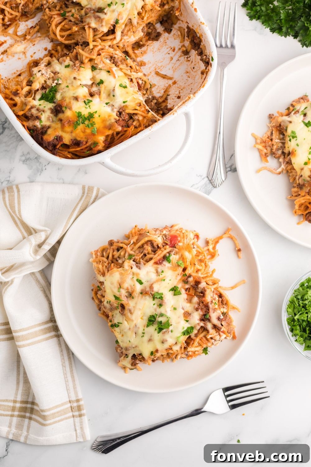 Million Dollar Spaghetti Casserole served in the pan and on individual plates, garnished with fresh herbs and ready for guests