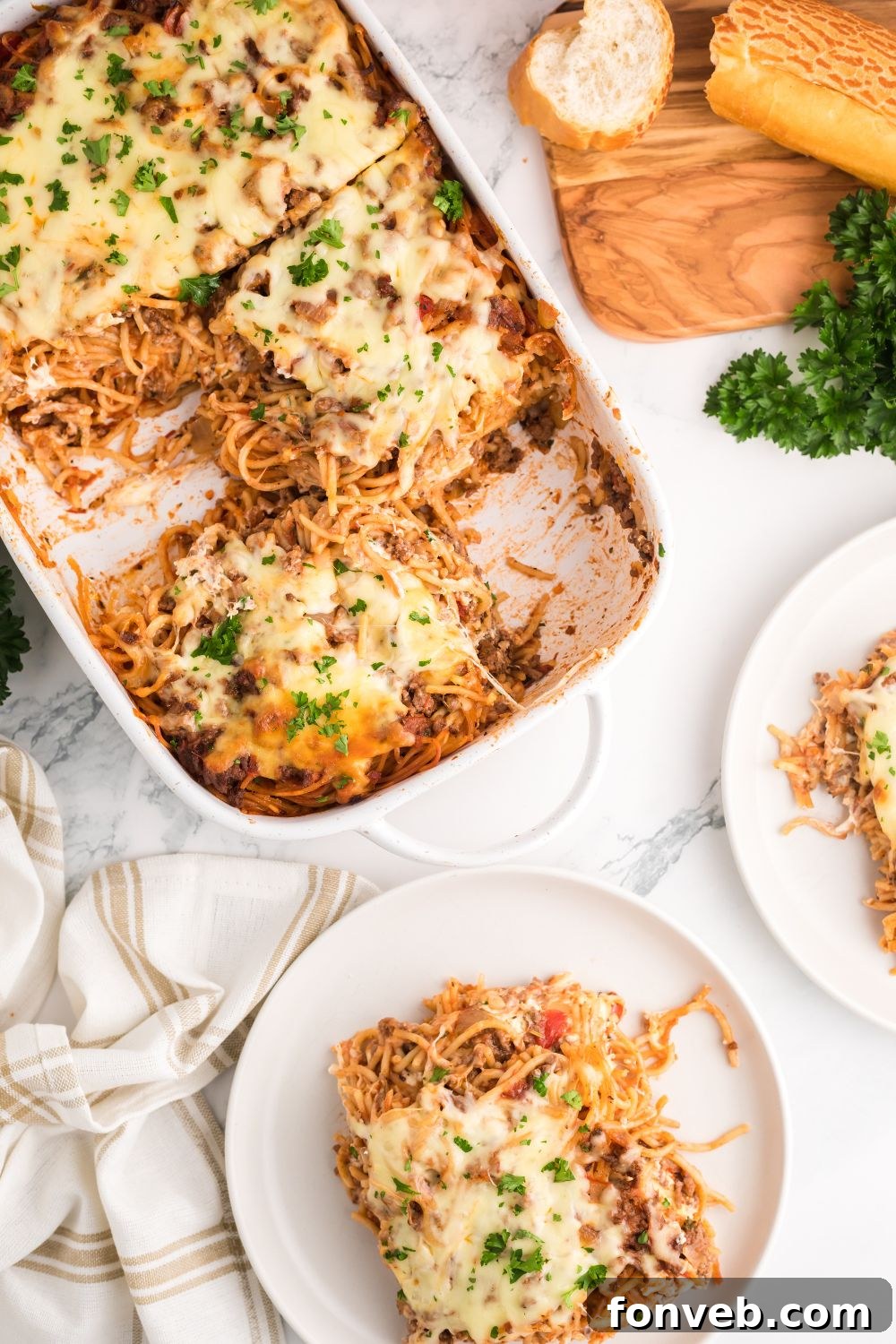 Million Dollar Spaghetti Casserole in a large baking pan, with individual servings on plates and side dishes like bread