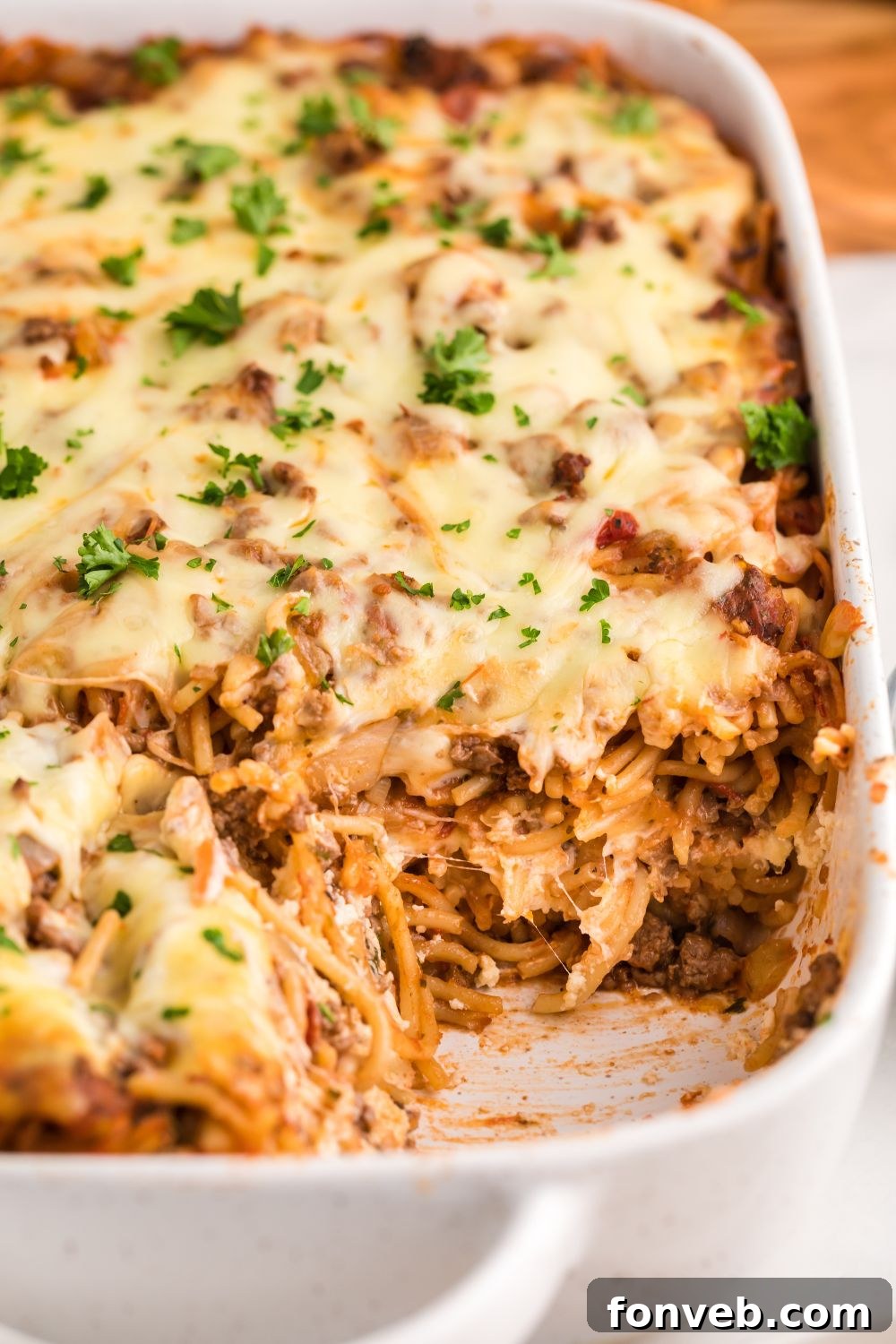 Million Dollar Spaghetti Casserole in a pan with some removed, showcasing the layers and golden top