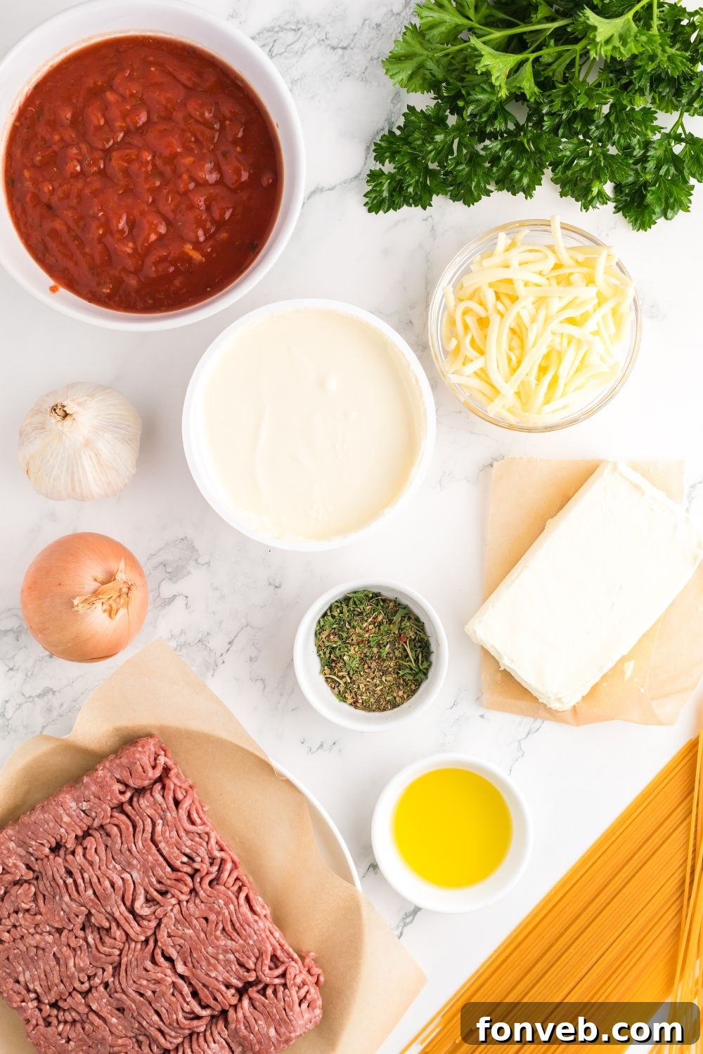 Key ingredients for Million Dollar Spaghetti Casserole laid out neatly on a rustic wooden table, including pasta, sauces, cheeses, and aromatics