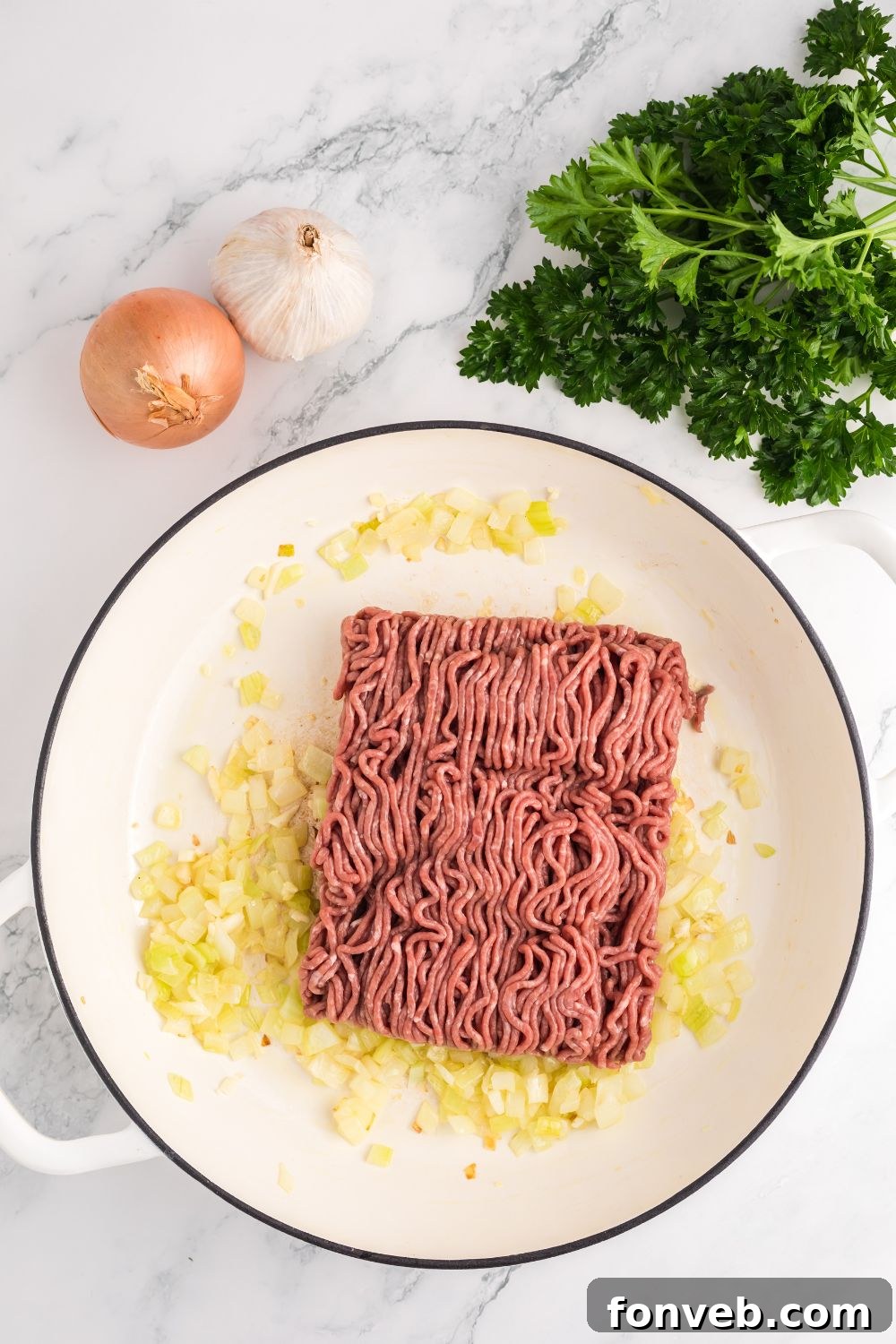 Sautéed onions and browning ground beef in a large skillet, forming the base of the rich meat sauce