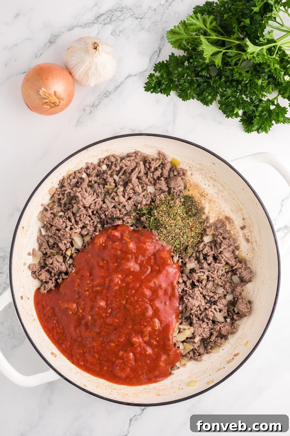 Ground beef cooking with pasta sauce and Italian seasoning simmering together in a pot