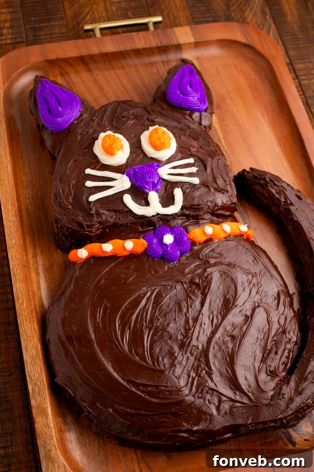 Purrfectly Simple 4-Ingredient Black Cat Halloween Cake 13 Homemade Halloween cake in the shape of a cat sitting on a rustic cutting board, ready to be sliced