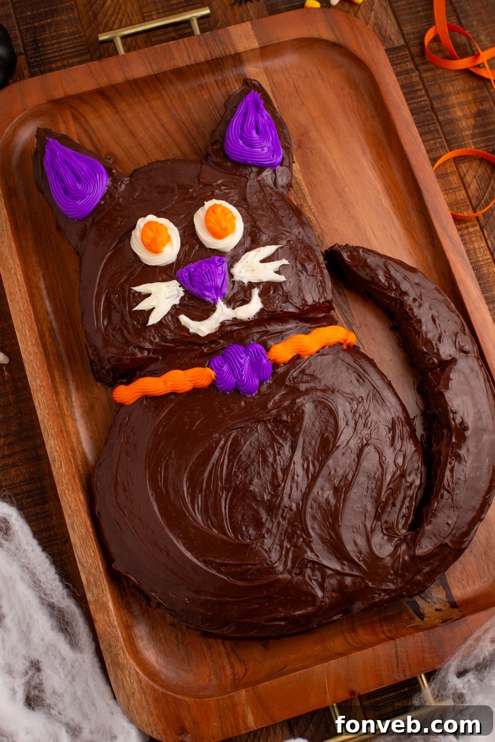 Purrfectly Simple 4-Ingredient Black Cat Halloween Cake 15 Easy Halloween Black Cat Cut Out Cake on a serving tray with fake spider webs around bottom of tray, creating a spooky atmosphere
