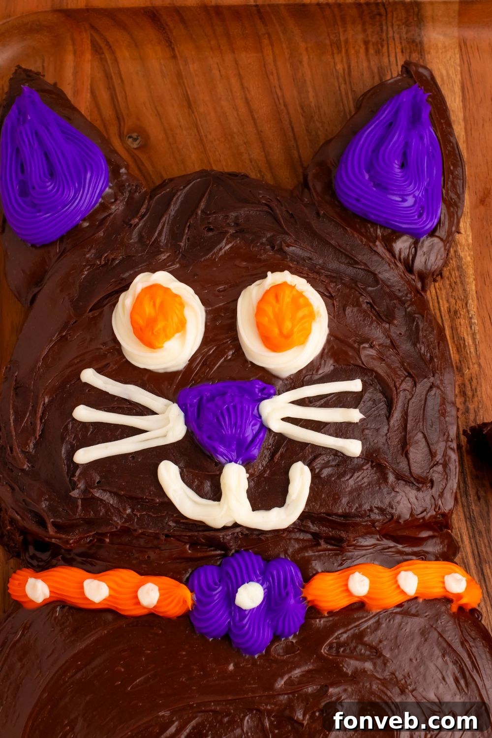 Purrfectly Simple 4-Ingredient Black Cat Halloween Cake 16 Close up of the face of the cat cake for Halloween on a wooden table tray, showing the adorable expression