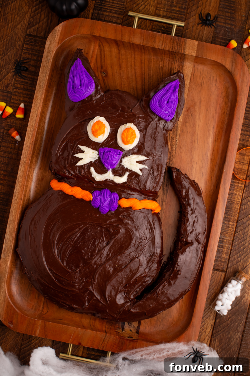 Purrfectly Simple 4-Ingredient Black Cat Halloween Cake 3 Easy Halloween Black Cat Cut Out Cake on a serving tray on table with some candy corn to the side, showcasing its detailed decoration