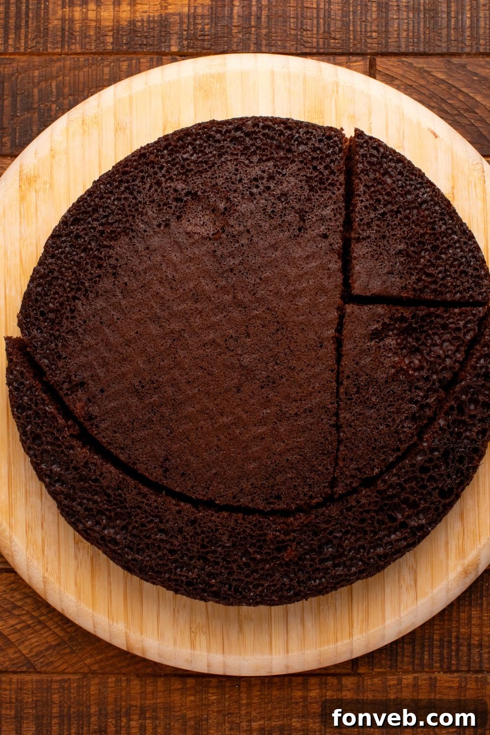 Purrfectly Simple 4-Ingredient Black Cat Halloween Cake 6 One round cake being carefully cut into pieces to shape into a cat, showing the initial cuts