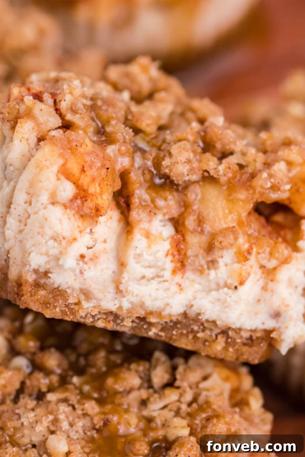 close up of Apple Crisp Cheesecake Bite with part of it eaten with more cheesecakes around the main bite