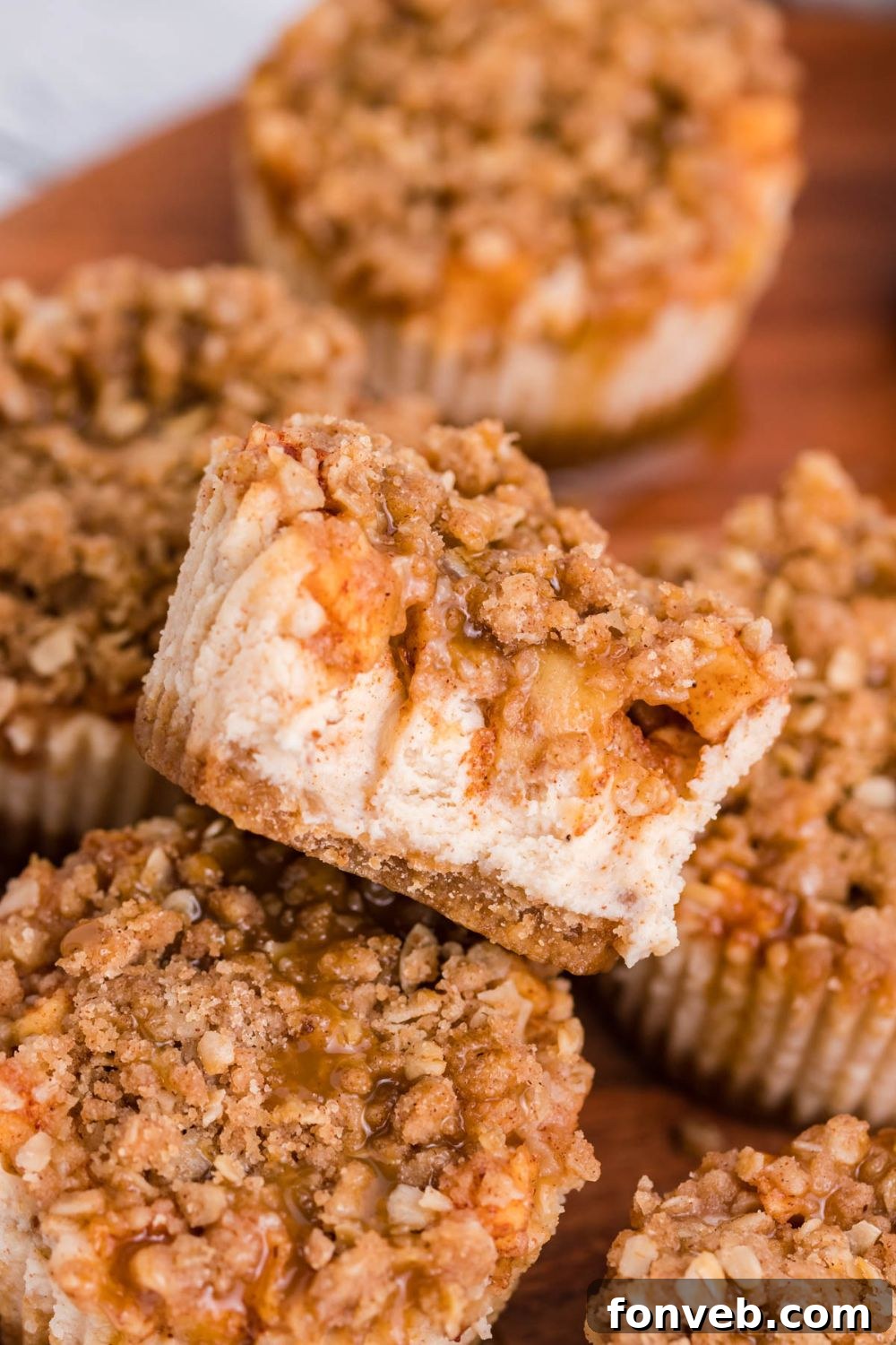 marble counter with a wooden cutting board on table with Apple Crisp Cheesecake Bites scattered on the board 