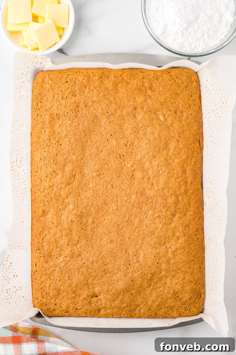 Classic Spiced Pumpkin Roll 11 baked Pumpkin Cake Roll in a sheet pan sitting on a marble countertop