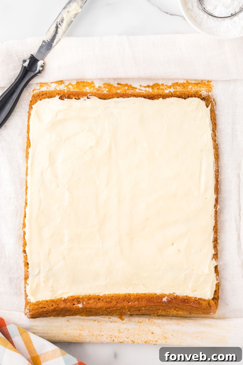 Classic Spiced Pumpkin Roll 15 pumpkin roll laid out on marble counter spread with cream cheese filling all over