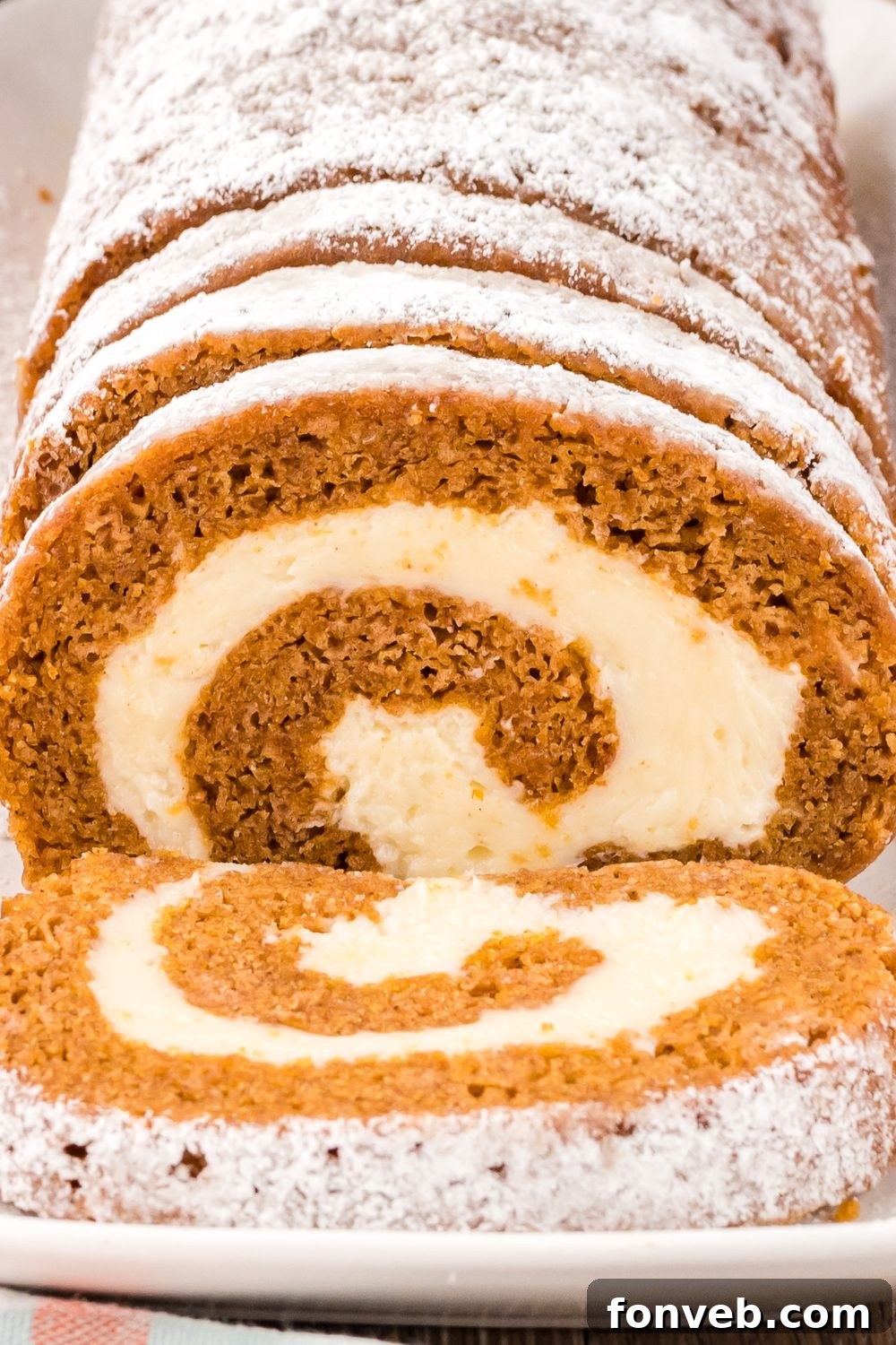 Classic Spiced Pumpkin Roll 20 close up of Pumpkin Cake Roll on a platter so you can see the swirl of filling in the pumpkin roll