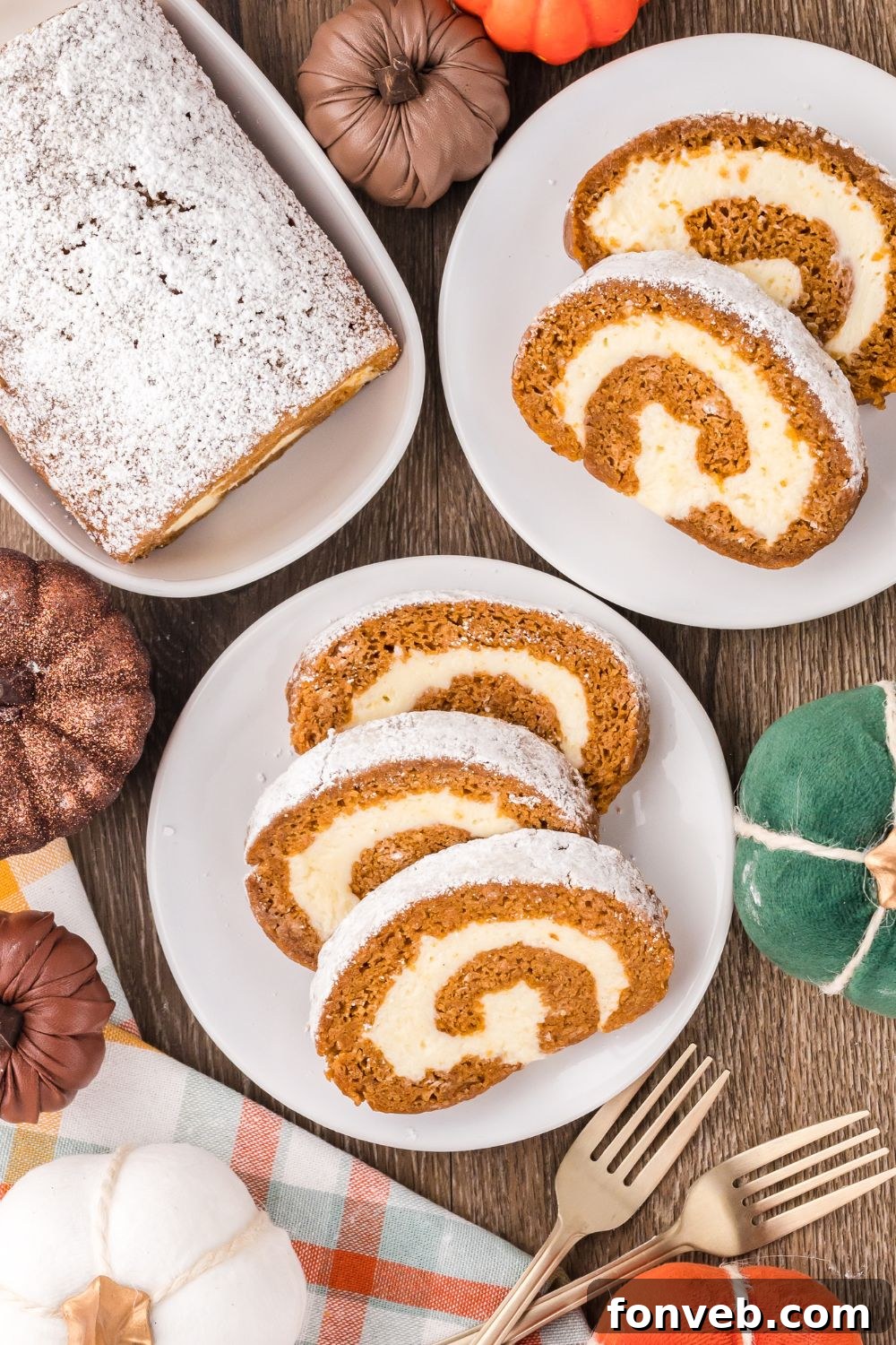 Classic Spiced Pumpkin Roll 22 fall rustic wooden table with faux pumpkins and plates with slices of Pumpkin Cake Roll on it, and a platter to the back with more of the pumpkin cake on it