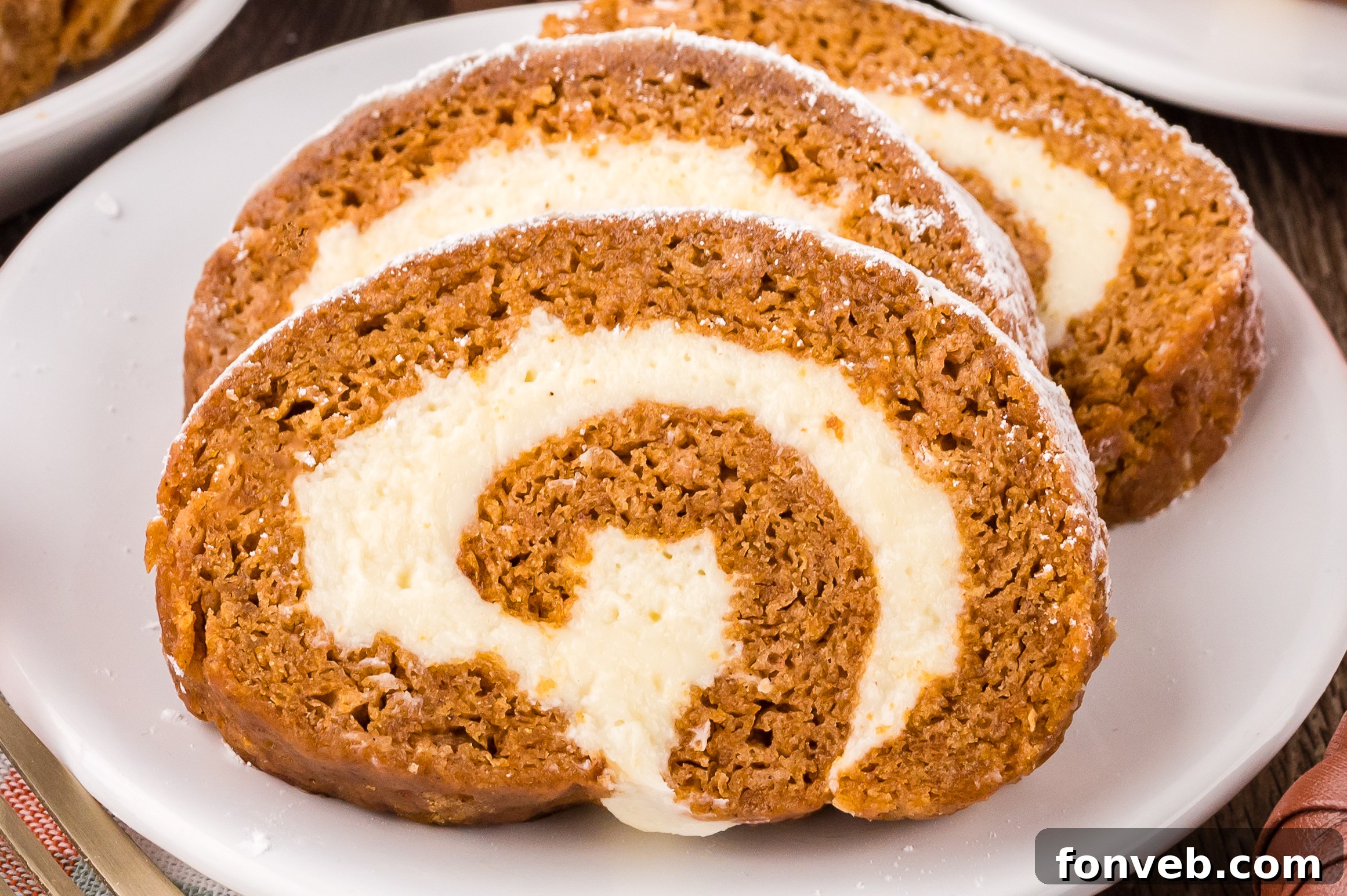 Classic Spiced Pumpkin Roll 30 Pumpkin Cake Roll sliced on white plates placed on table with a few faux pumpkins around